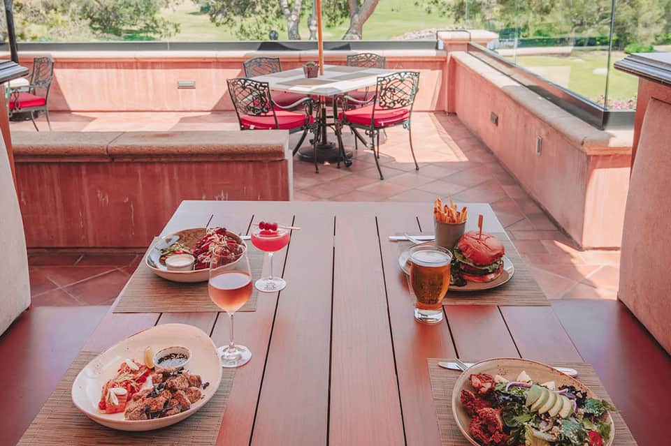 Rooftop dining with plated cuisine, cocktails, and panoramic views of green landscape