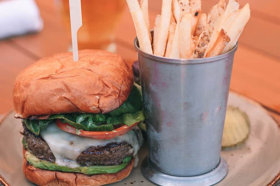 Gourmet burger with lettuce and tomato served with golden fries in metal cup