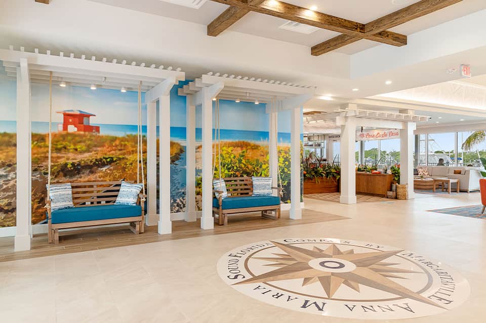 Bright coastal-themed lobby with compass floor design and beach scene murals