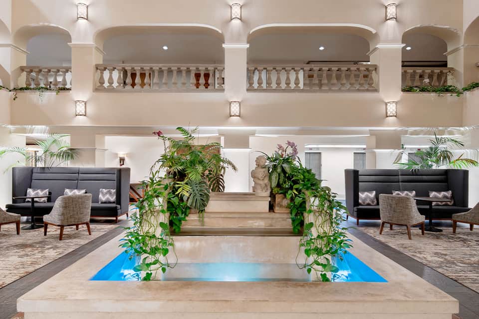 Luxury hotel lobby with grand columns, decorative indoor fountain, and seating areas
