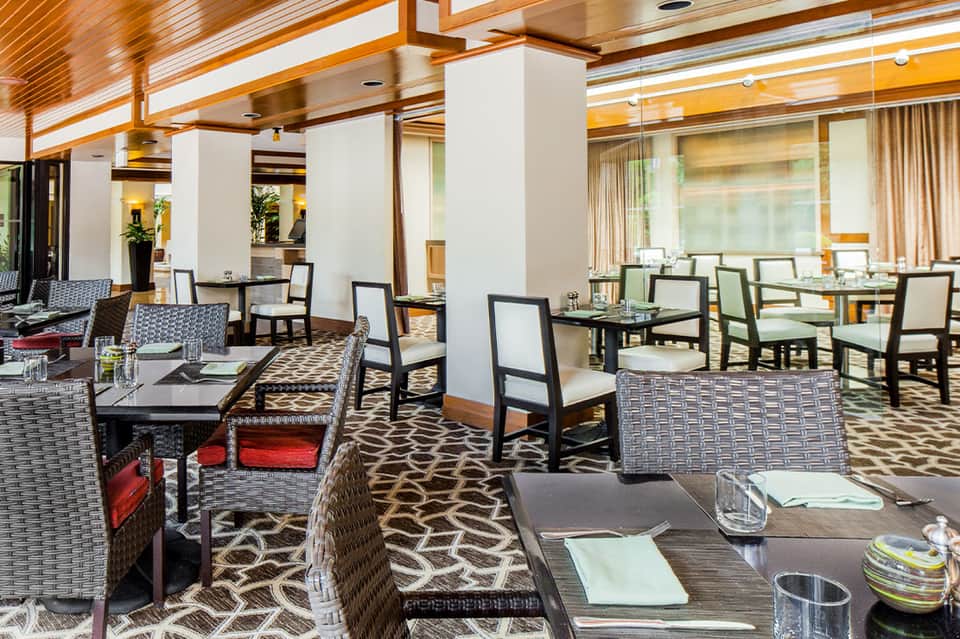Modern hotel restaurant dining area with geometric patterned carpet and contemporary wood furnishings