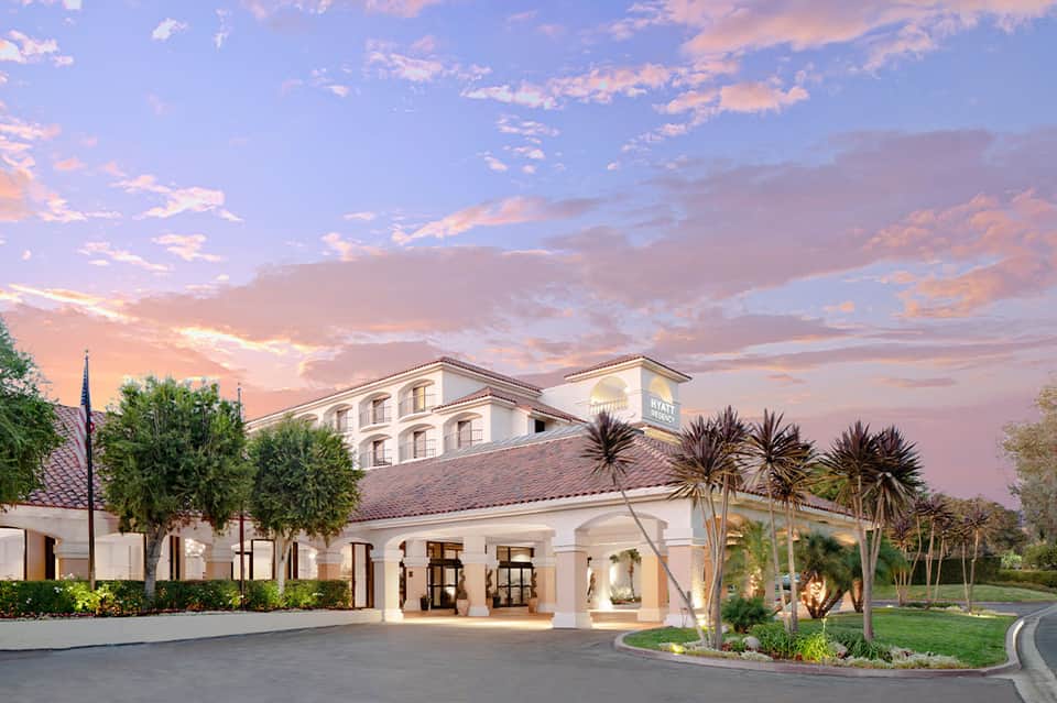 Luxury resort exterior at sunset with white columns, palm trees, and manicured grounds