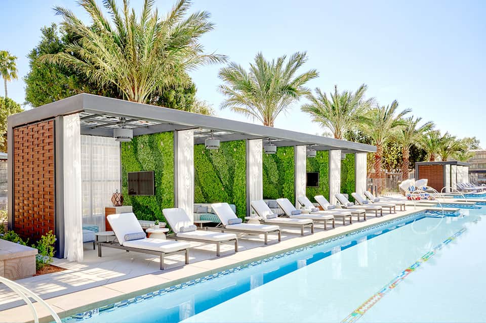 Modern pool cabanas with white columns and green living walls alongside lap pool