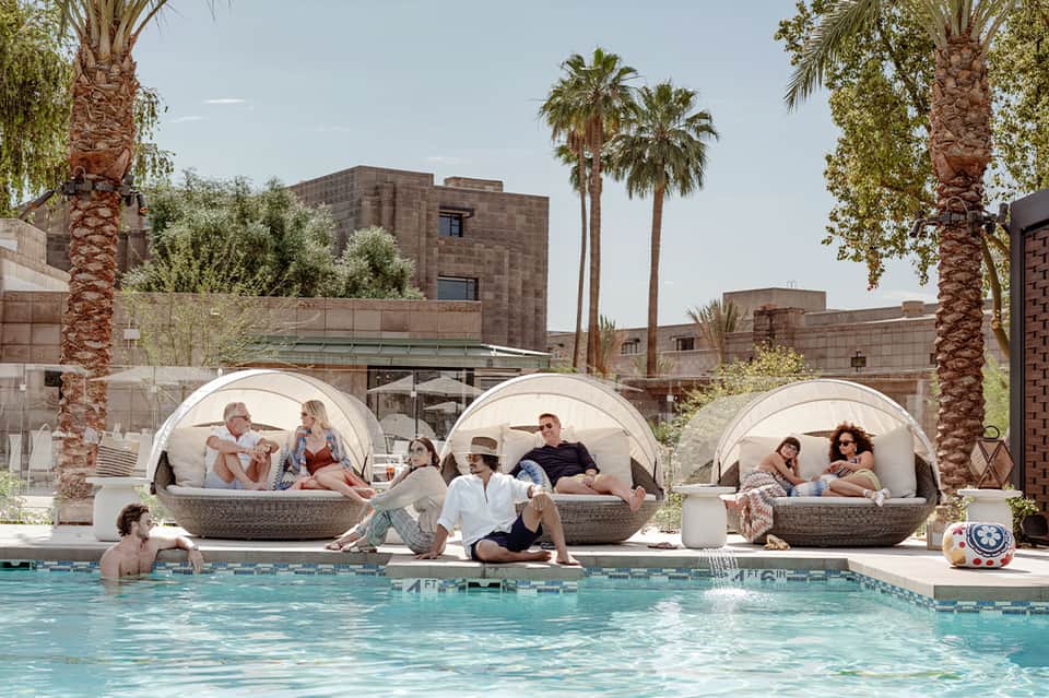 Resort pool with three large rounded pod lounges and guests relaxing poolside