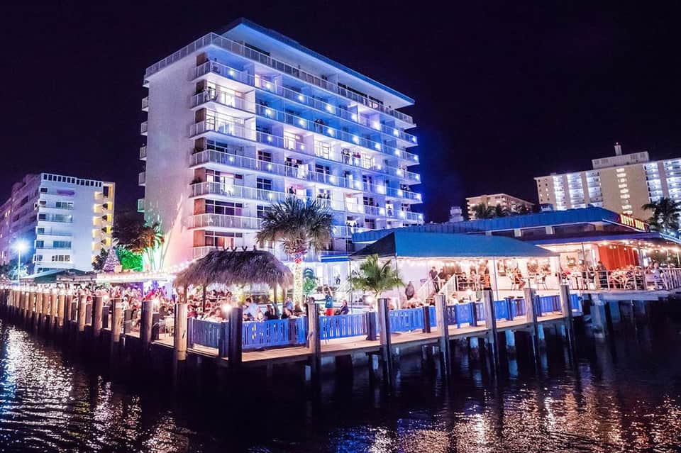 Waterfront resort at night with illuminated multi-story building, docked boats, and dining pavilion