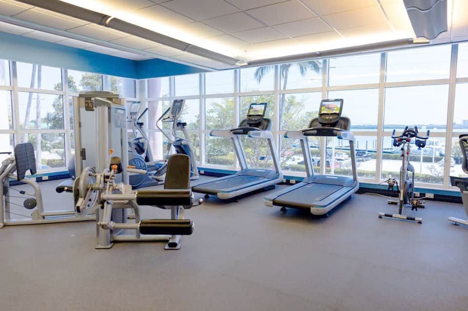 Modern fitness center with treadmills, exercise bikes, and large windows with city views