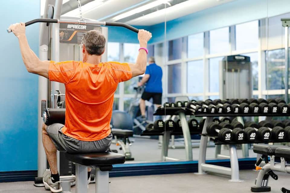 Man exercising on pull-up bar in modern gym with weights