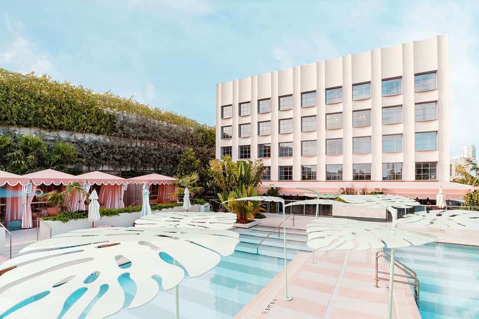 Resort pool area with pink striped cabanas, loungers, and modern building backdrop
