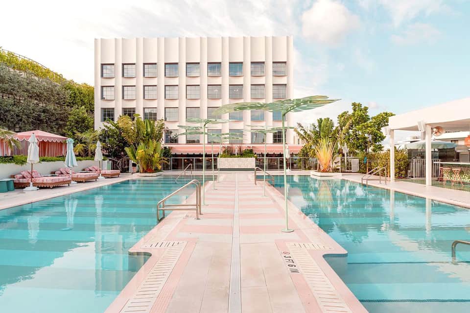 Symmetrical view of a pristine lap pool with pink diving boards and mid-century modern building