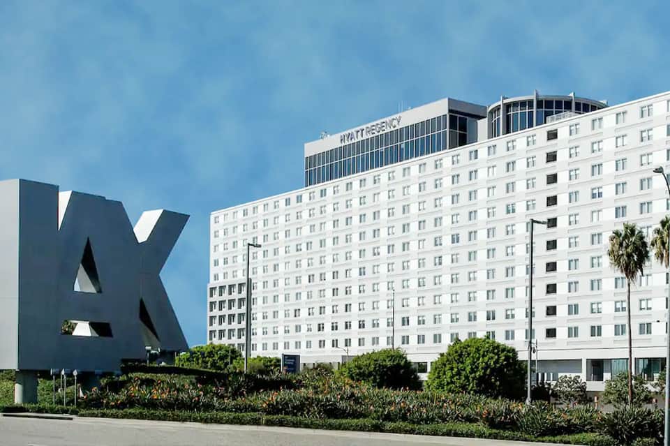 White Hyatt Regency hotel building with multi-story facade and palm trees