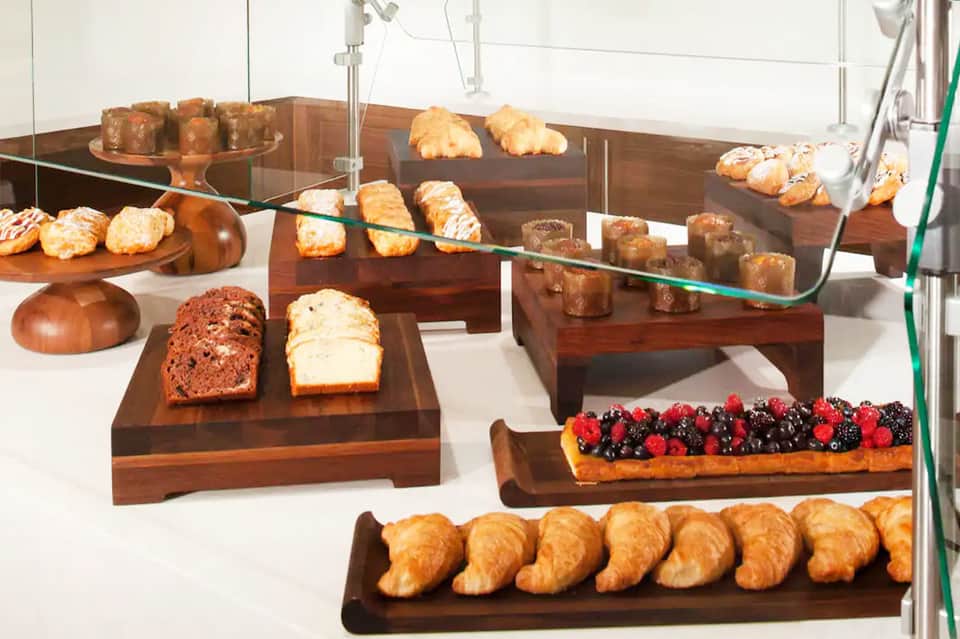 Bakery display with croissants, bread loaves, pastries, and fresh berries on wooden shelves