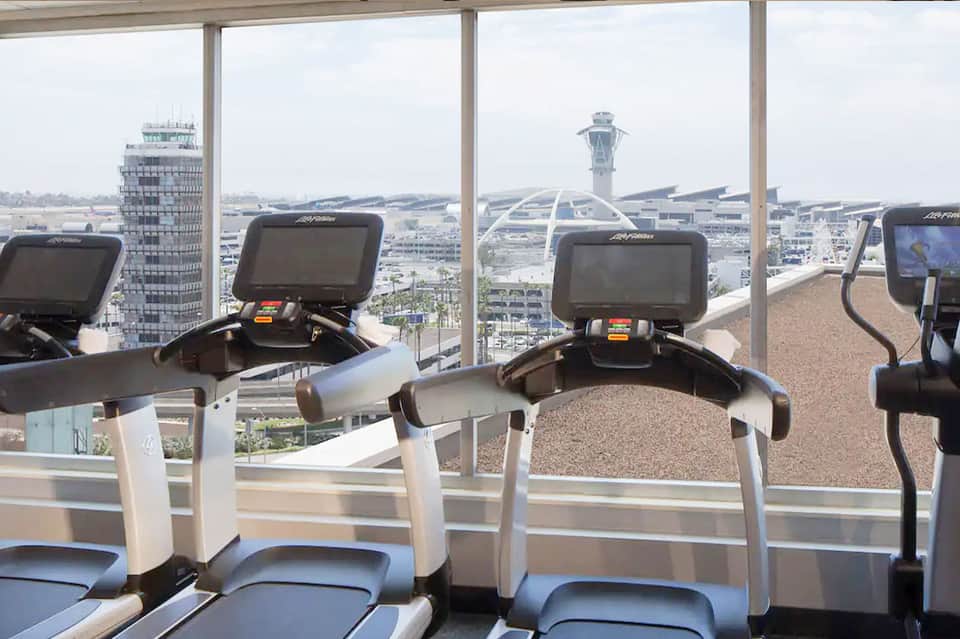 Gym with treadmills overlooking an airport control tower and runway through large windows