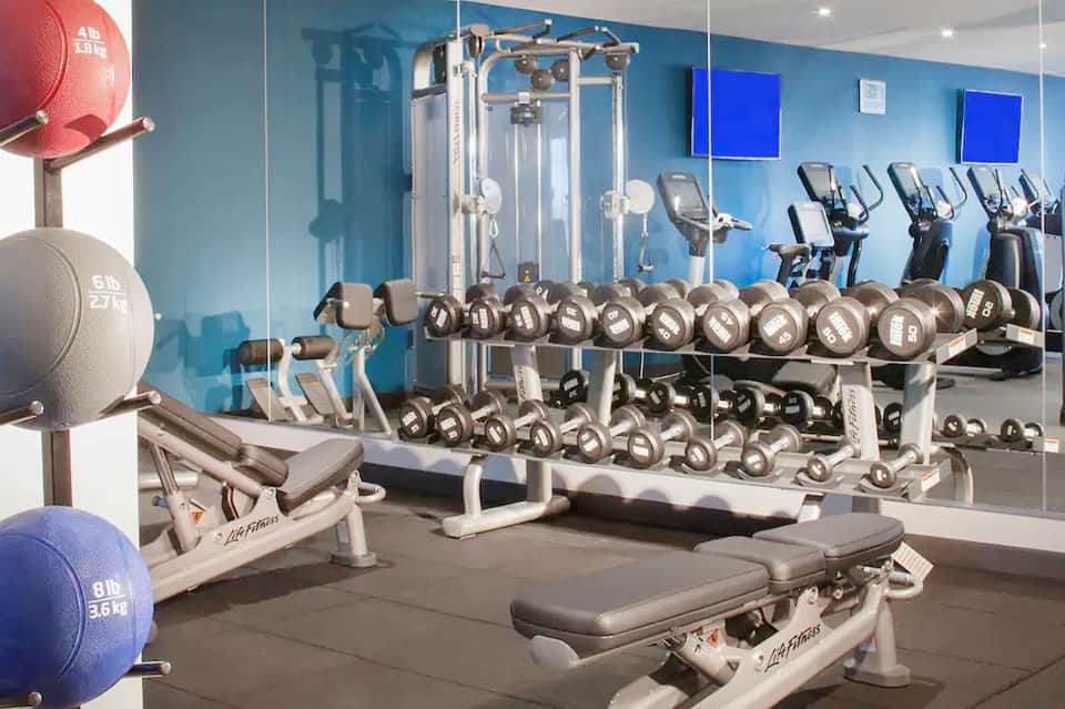 Modern fitness center with dumbbells, exercise machines, and mirrored walls