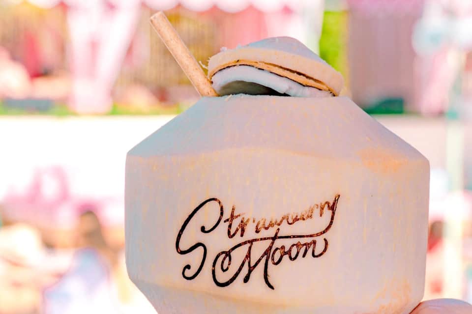 Strawberry cocktail with branding, focused shot with blurred pink tropical background
