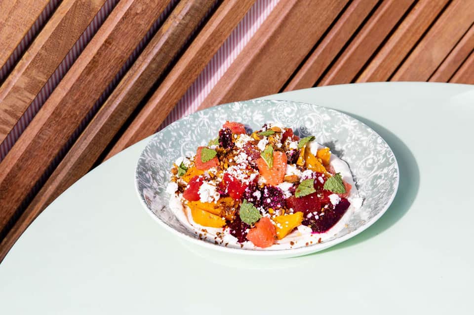 Colorful beet and vegetable salad with feta cheese and fresh herbs served on white plate