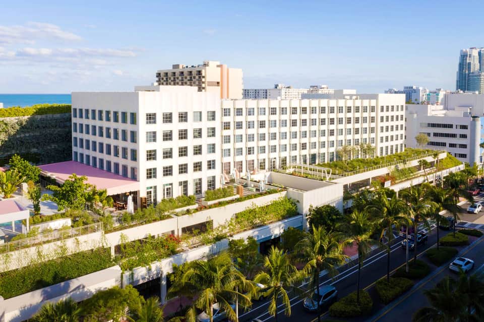 Aerial view of waterfront resort buildings with lush green rooftop terraces and ocean view