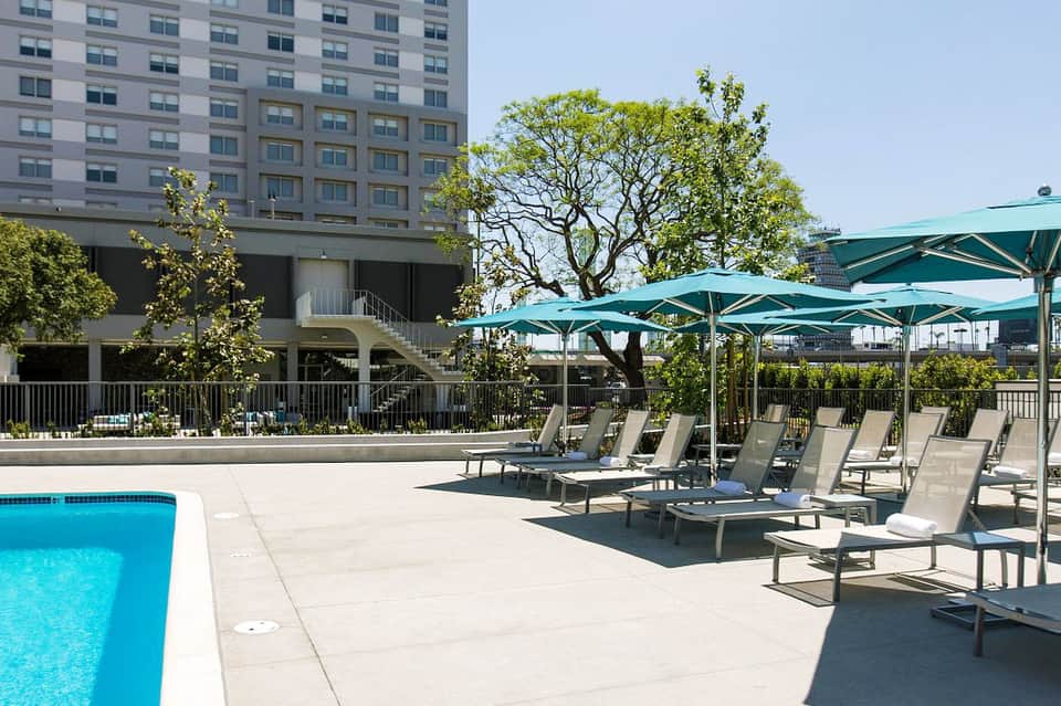 Modern hotel pool deck with lounge chairs and green umbrellas