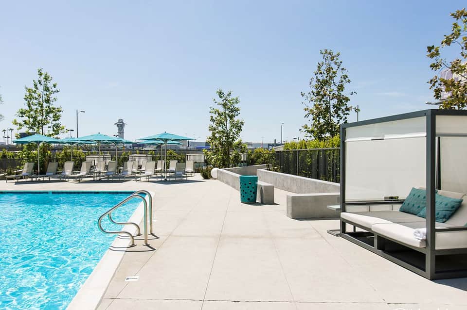 Resort rooftop pool deck with turquoise umbrellas, loungers, and city skyline views