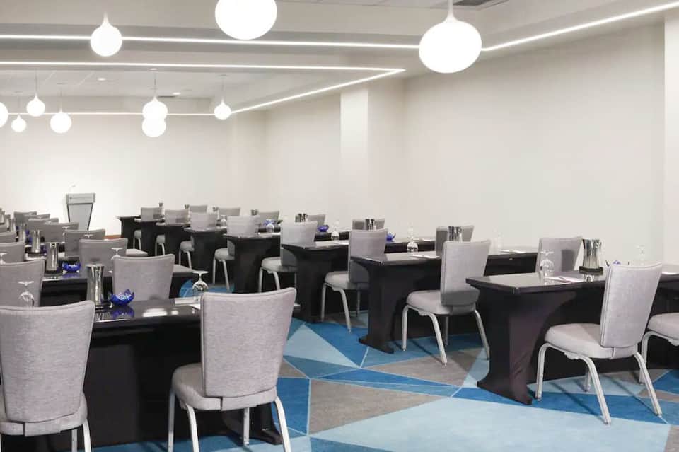 Contemporary dining room with round pendant lights, black tables, gray chairs, and geometric blue floor pattern