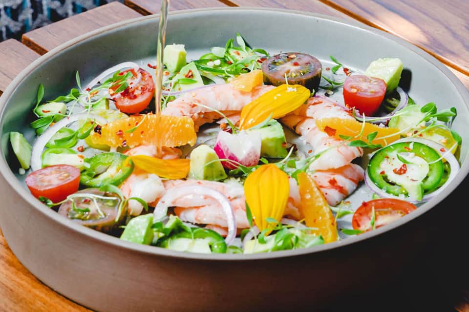 Colorful seafood ceviche dish with shrimp, citrus, and edible flowers