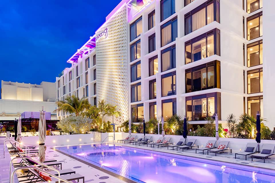 Luxurious modern hotel with illuminated pool at night, palm trees, and contemporary architecture