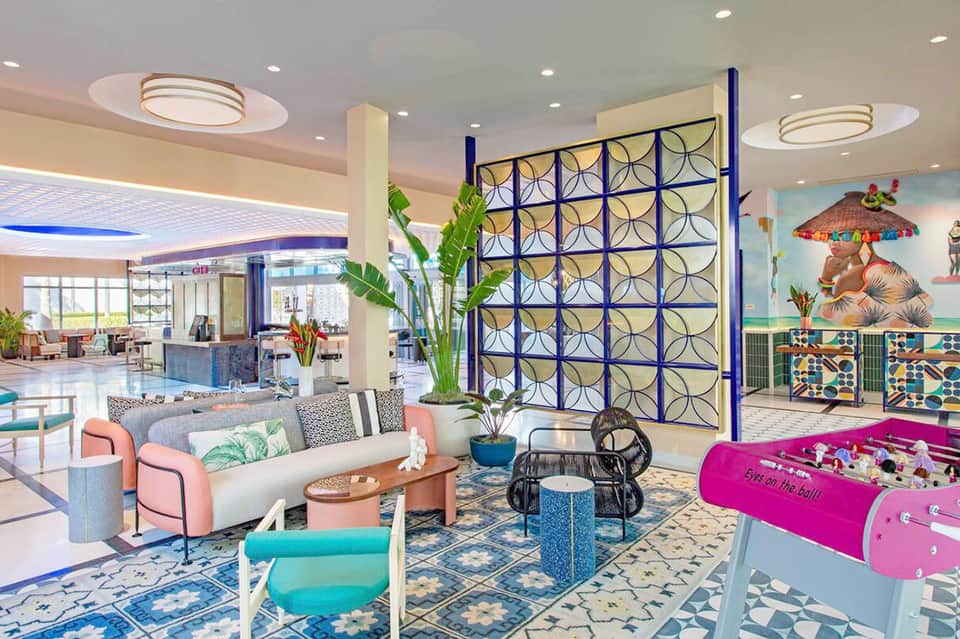 Modern hotel lobby with colorful geometric wall art, foosball table, and contemporary seating