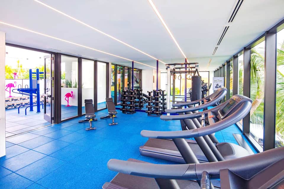 Modern fitness center with rows of treadmills, weights, and exercise equipment on blue flooring