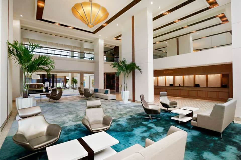 Modern hotel lobby with high ceilings, gold fixtures, and contemporary seating areas