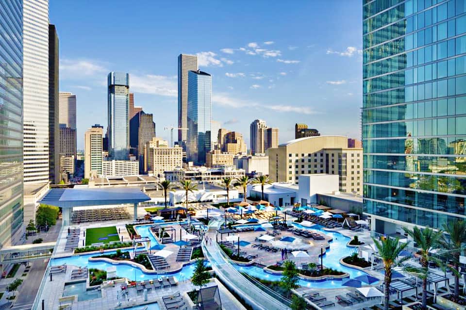Aerial view of downtown Houston skyline with resort pool complex featuring water slides and lounging areas