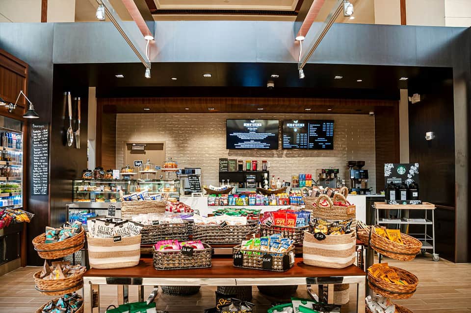 Bright hotel café interior with brick counter, menu boards, and baskets of snacks and beverages