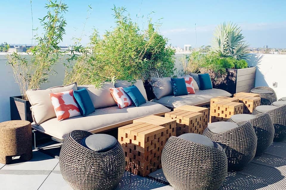 Upscale rooftop lounge with modern sectional seating, decorative pillows, and city skyline view