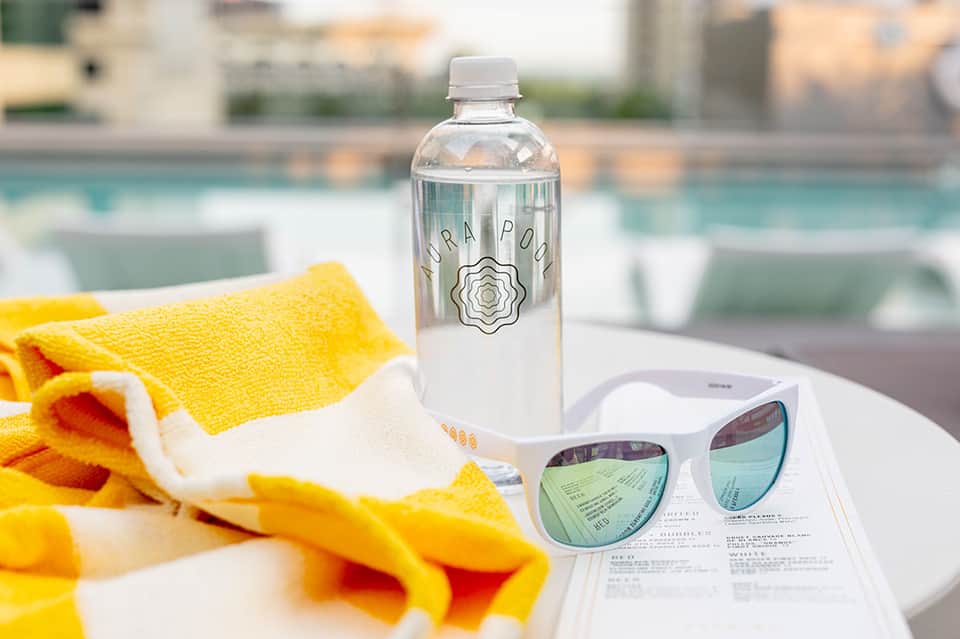 Poolside items including water bottle, sunglasses, yellow towel, and resort loungers