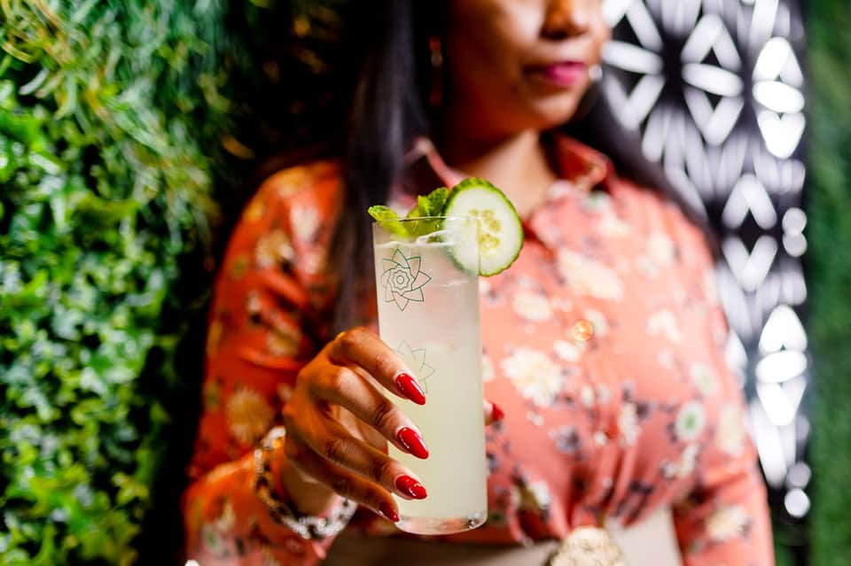 Woman holding cucumber mojito cocktail in garden setting