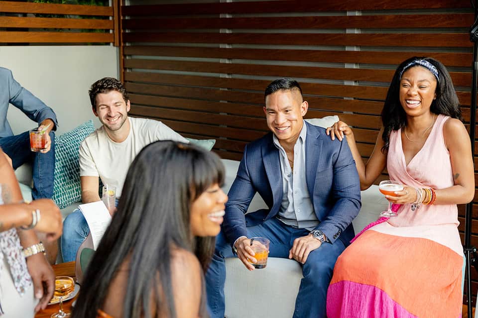 Group of guests socializing at hotel bar with cocktails and wood paneling