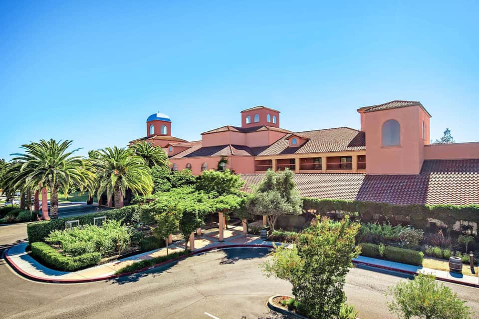 Spanish Colonial-style resort exterior with pink buildings, blue domes, and manicured gardens