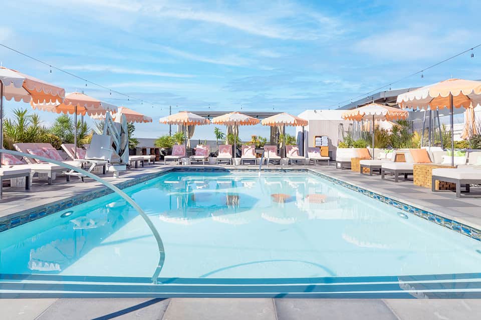 Modern rooftop pool with blue water, orange umbrellas, and contemporary lounge seating