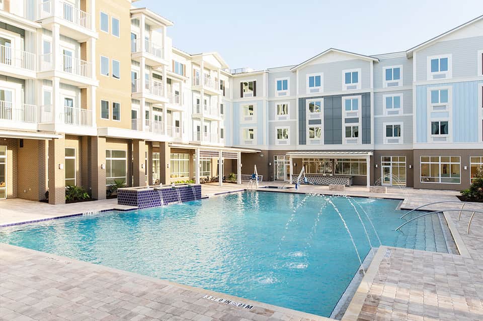 Modern apartment complex with pool, loungers, and multi-story residential buildings