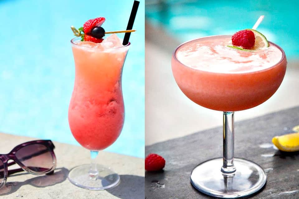 Two colorful cocktails poolside: pink drink with berries and tropical drink with fruit garnish