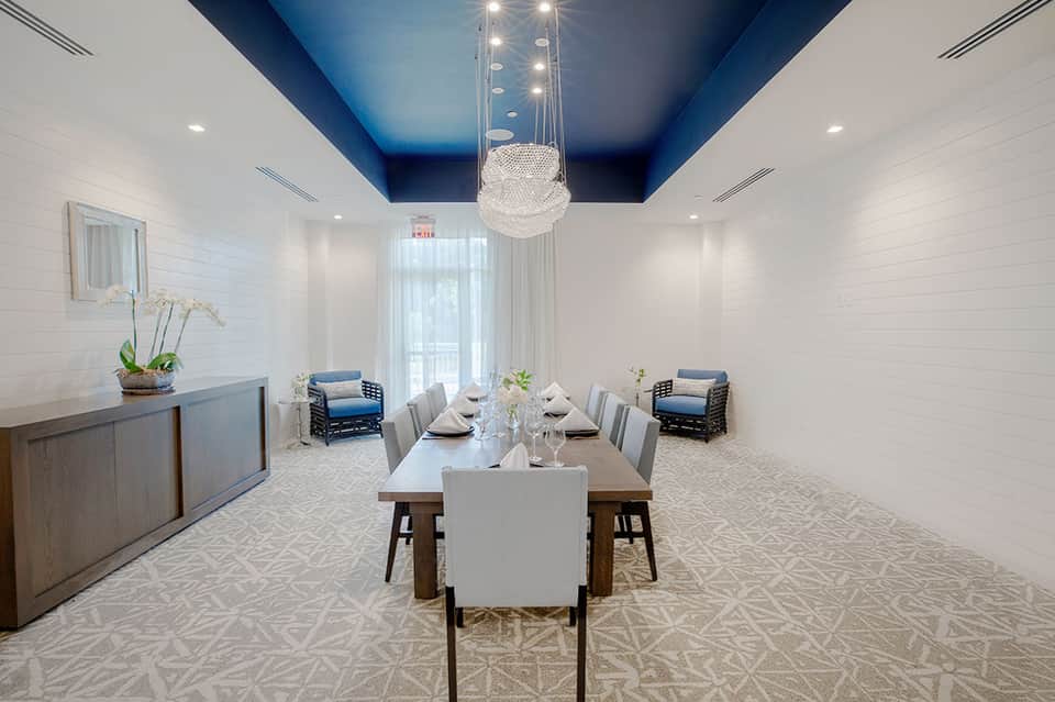 Modern private dining room with white shiplap walls, blue ceiling, crystal chandelier