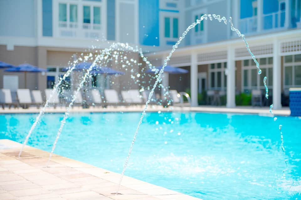 Crystal water fountain feature at resort pool deck with turquoise water and lounge chairs