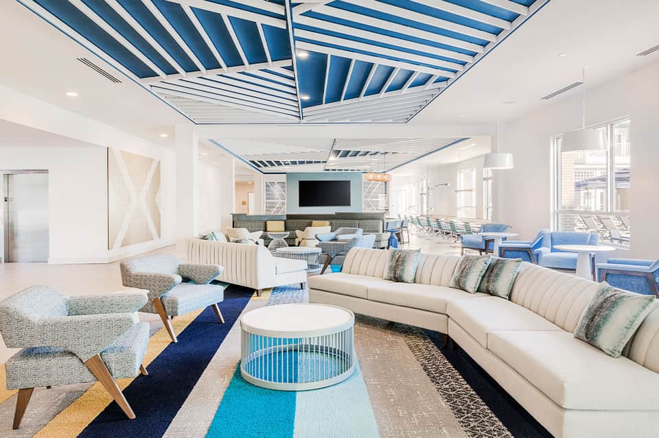 Modern lounge with striped blue ceiling, white sofas, and blue accents