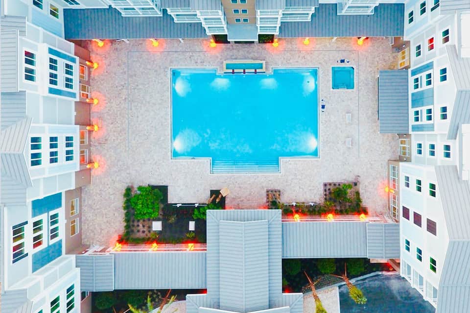 Aerial view of rectangular swimming pool surrounded by modern white hotel buildings with courtyards