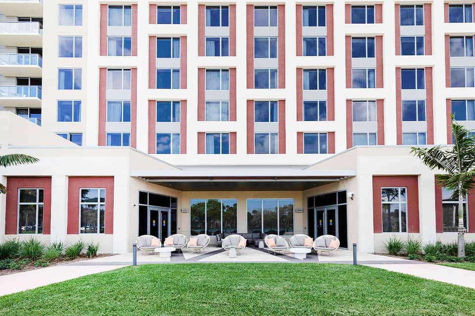 Contemporary hotel exterior with red and white geometric facade, ground-level seating area with curved chairs