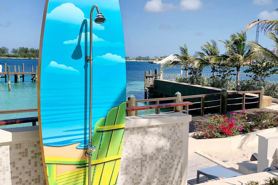 Beachfront resort with blue surfboard and shower station overlooking turquoise water