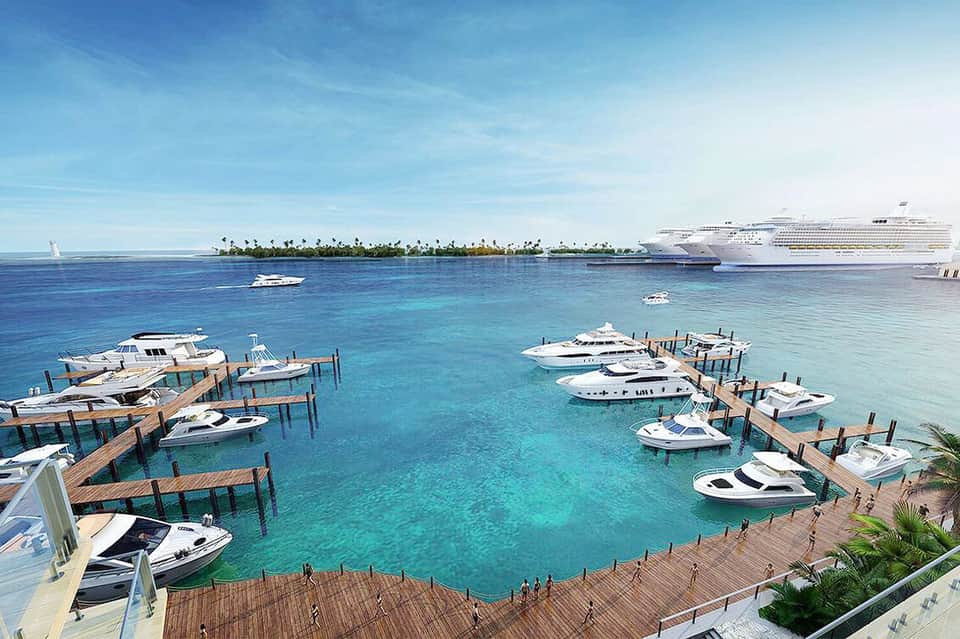 Marina with wooden docks, white boats, and luxury cruise ship anchored in turquoise tropical waters