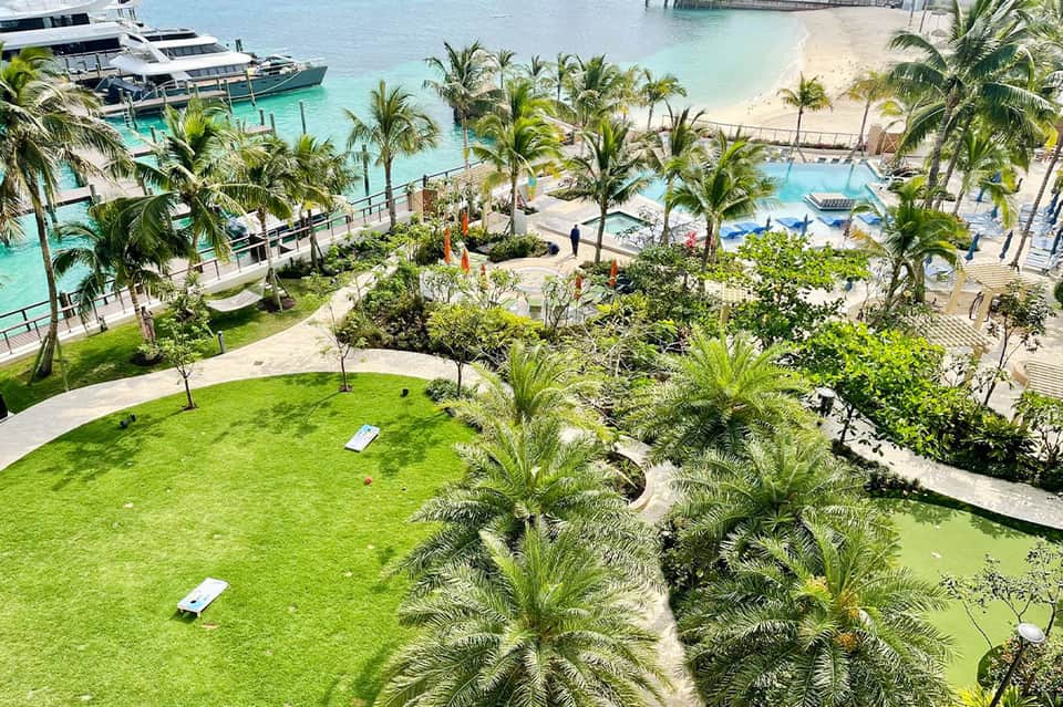 Aerial view of tropical beach resort with palm trees, turquoise water, and beachfront pools