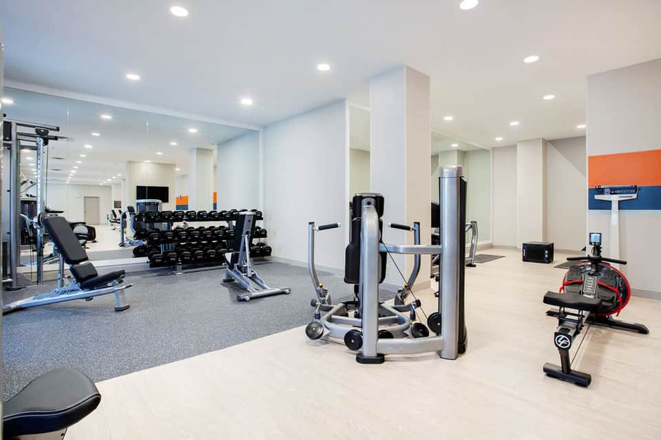 Modern fitness center with dumbbells, cardio machines, mirrors, and bright lighting