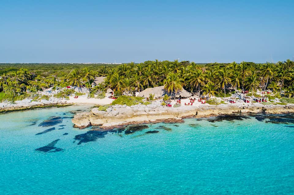 Aerial view of tropical beach resort with turquoise water, palm trees, and sandy coastline