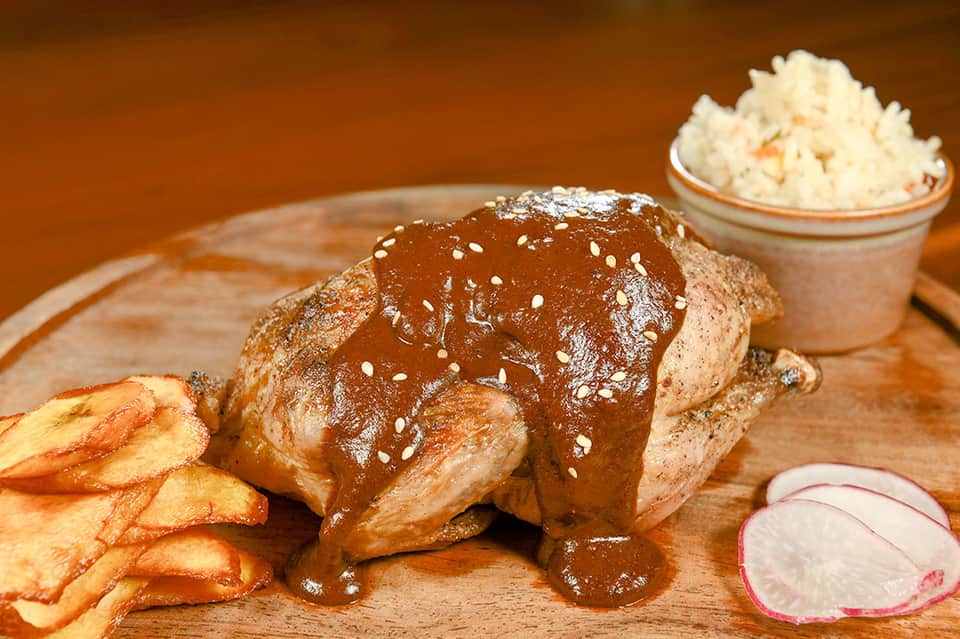 Grilled meat with sesame seeds, fries, and side dishes on a wooden serving board
