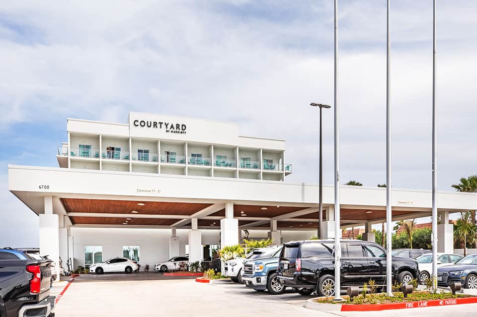 Modern Courtyard by Marriott hotel exterior with covered parking area and vehicles